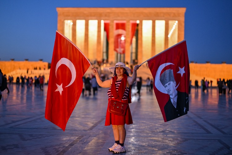 Arkasında anıtkabir olan elinde türk bayrağıyla poz veren küçük çocuk