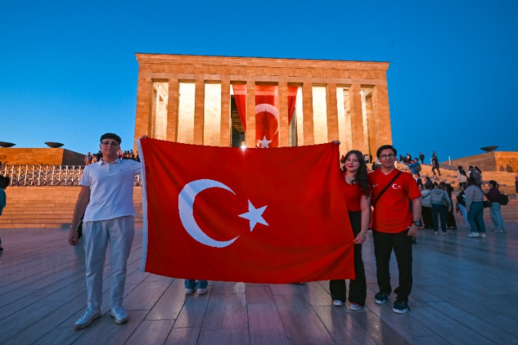 Arkasına anıtkabiri alıp ellerinde türk bayrağıyla poz veren vatandaşlar