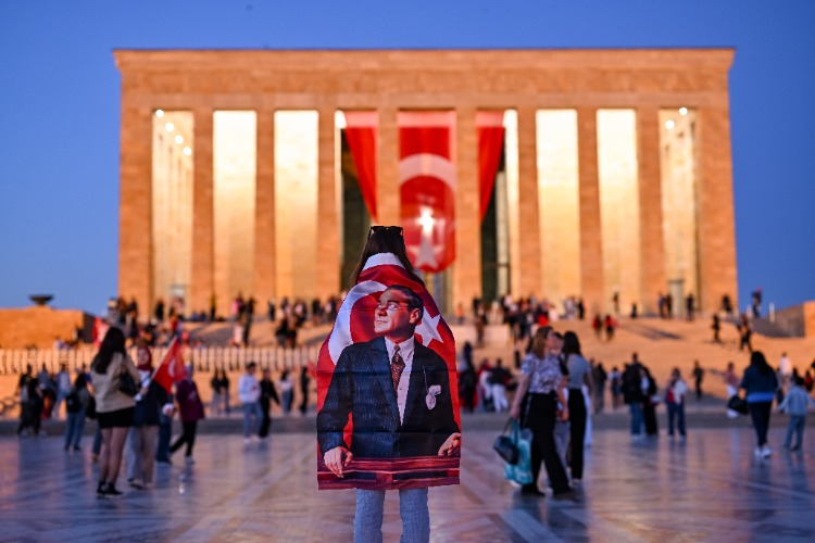Sırtında atatürk ve türk bayrağıyla anıtkabire karşı bakan bir vatandaş